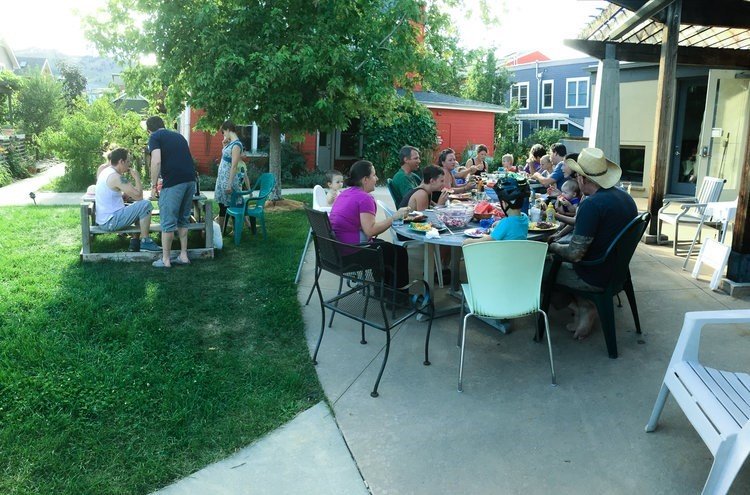 Woman with long light brown hair pinching the bridge of her nose with eyes closed, wearing a light pink top, against a light gray background